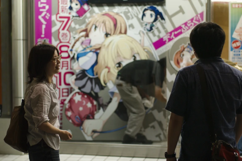 two young people standing in front of an anime poster