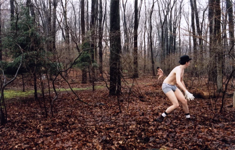 a woman walks through leaves with her dog