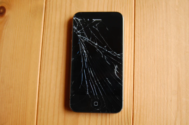 a broken cell phone is on a wooden table