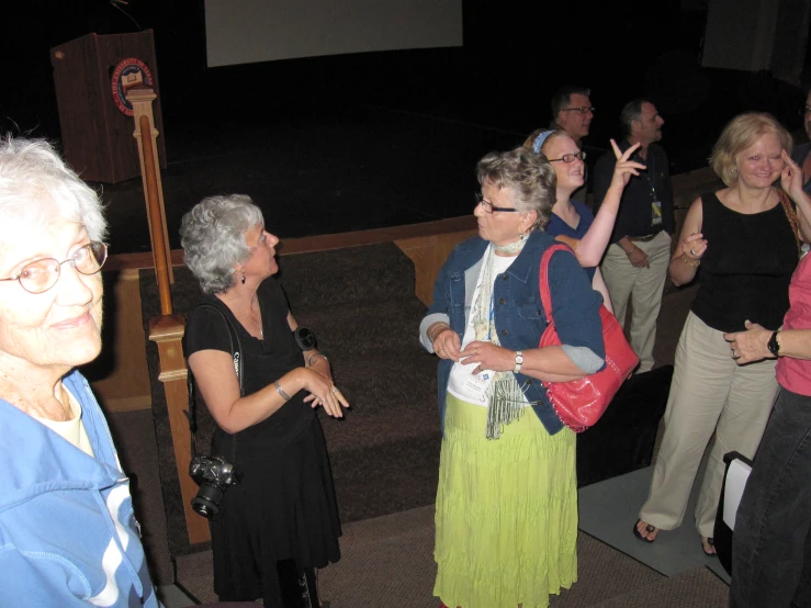 some older people are standing and clapping in front of the camera