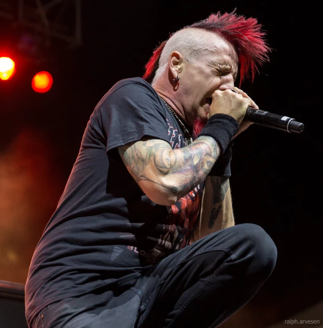 a man sitting on a stage singing into microphone