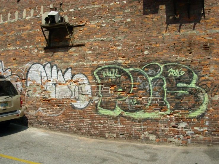 a white car parked next to a brick building with graffiti on it