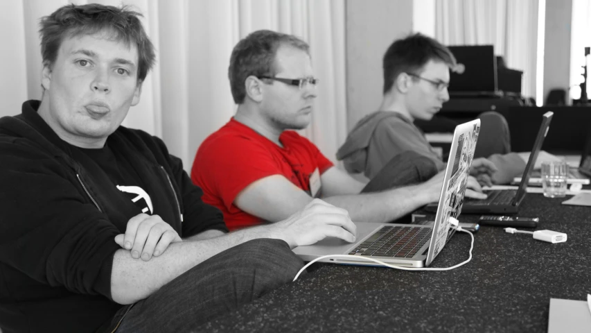 three men with their laptops on the table