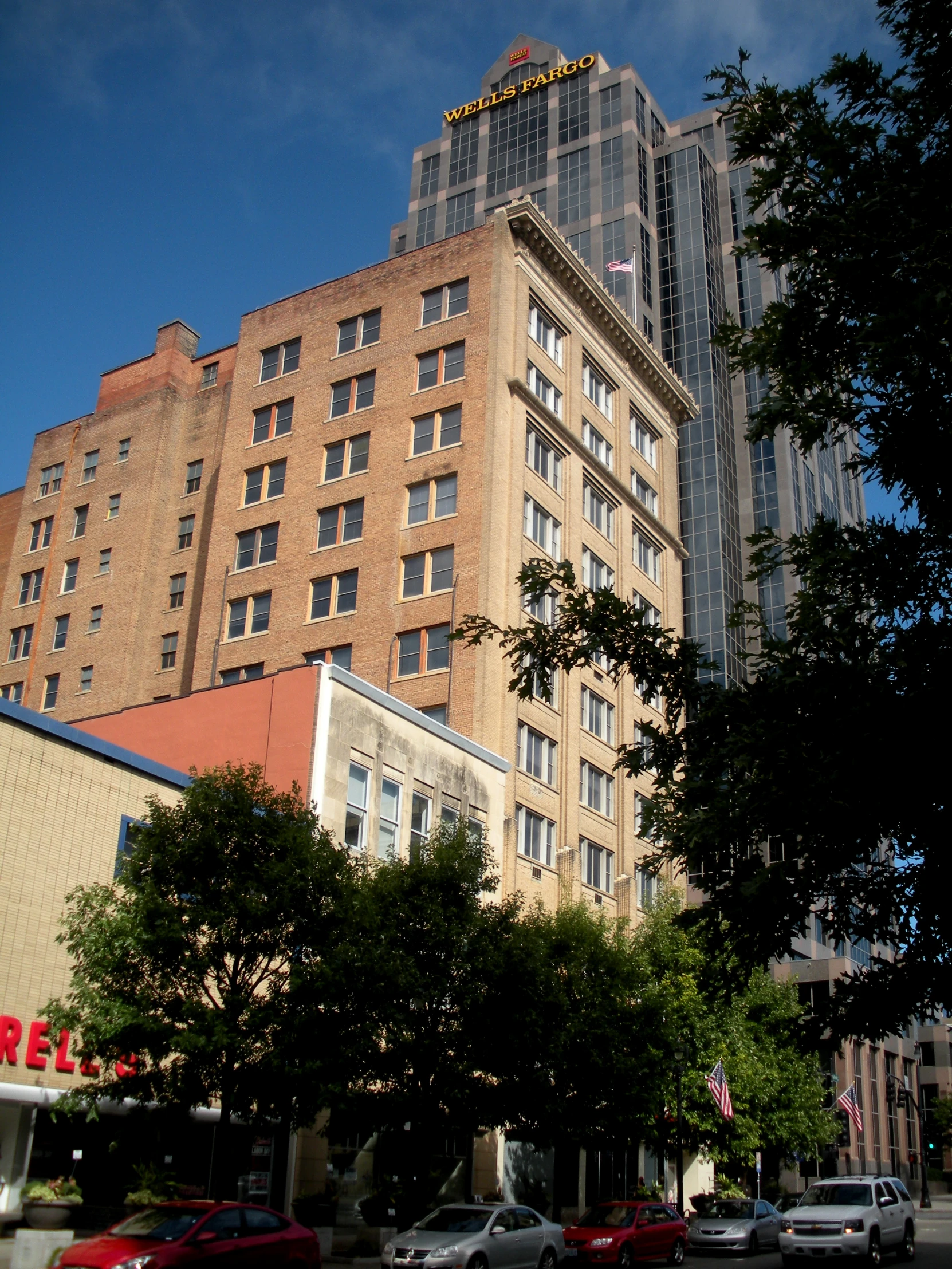 two large buildings on the corner with cars parked outside