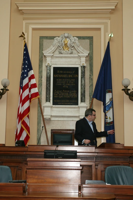 a man speaking in front of flags at a podium