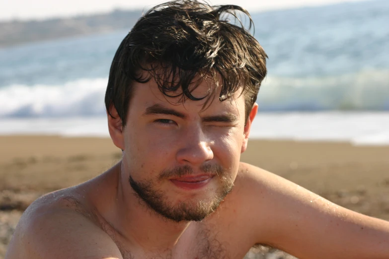 man with beard and frizz on the beach near water