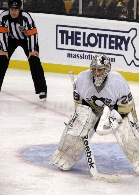 an ice hockey goaltender in white waiting to hit the puck