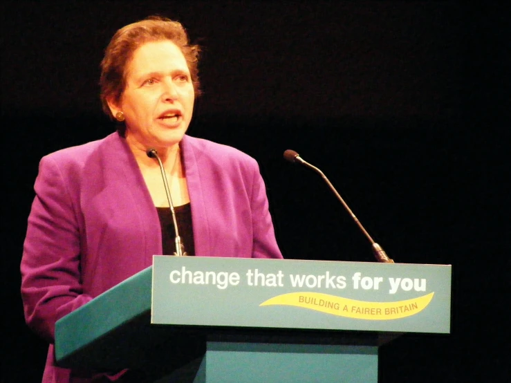 woman at a podium with a sign on it