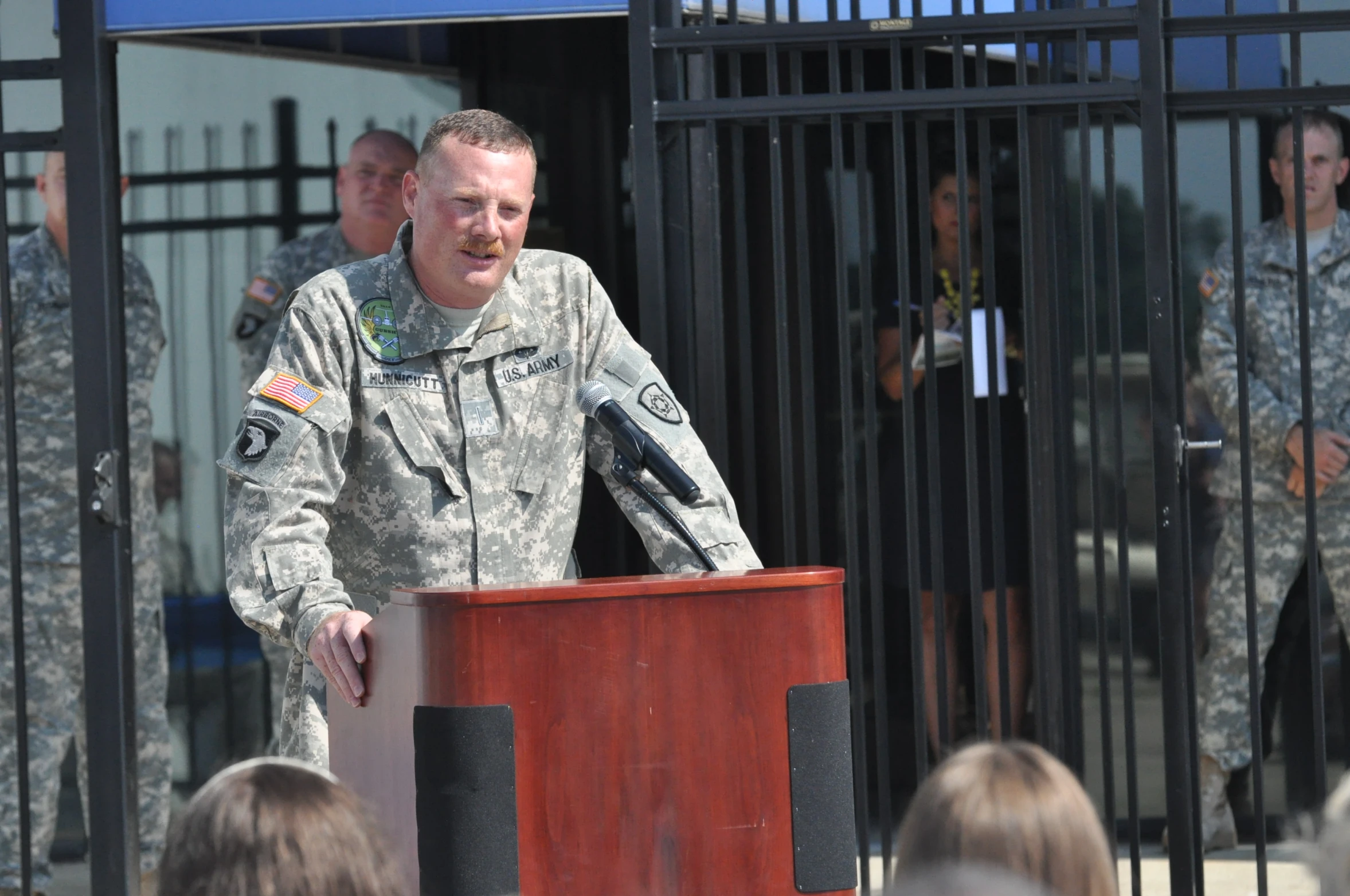 a man in army fatigues standing in front of a podium