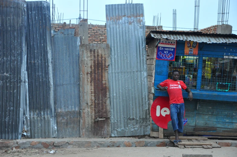 a man in red shirt standing by building next to a street