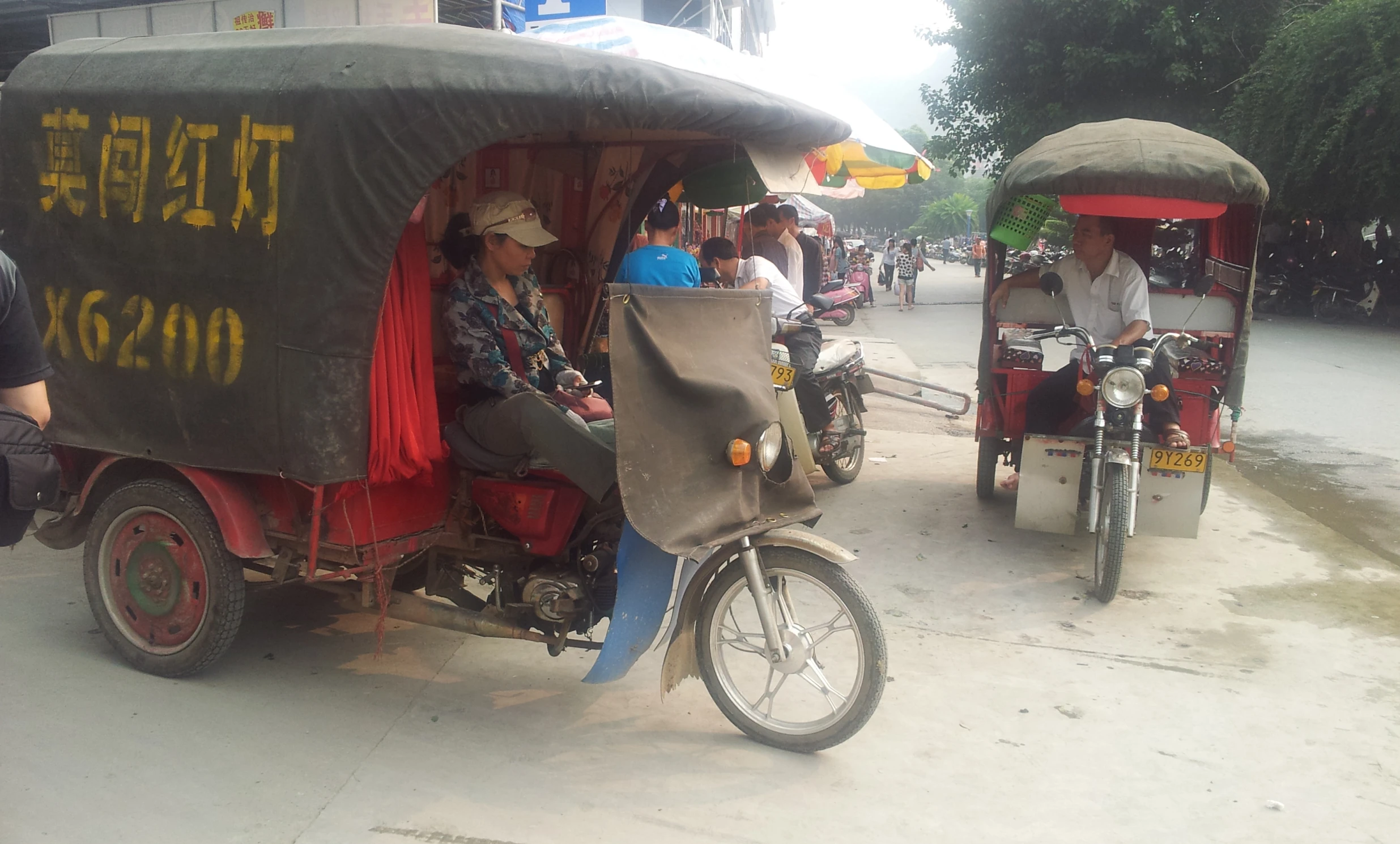 a person riding on the back of a motorcycle next to a man on a motor scooter