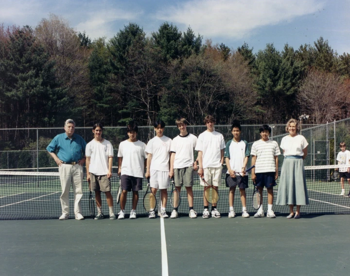 a tennis team pose for a picture on the court