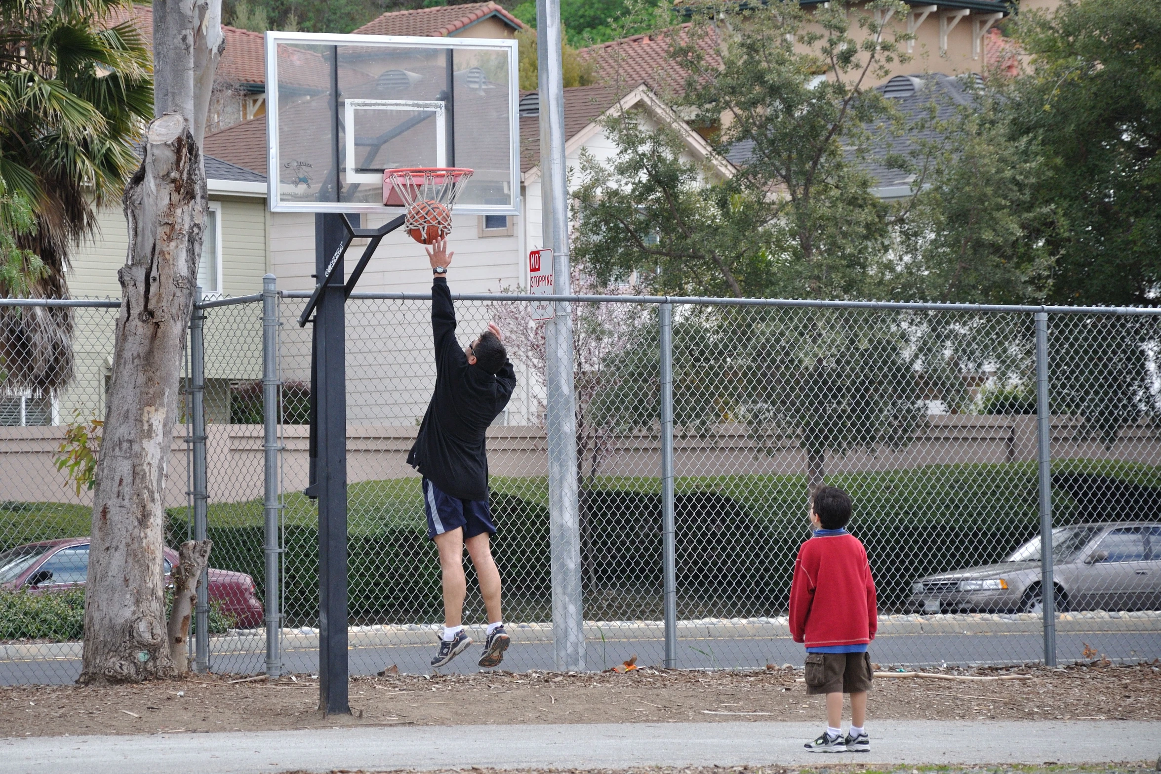 young men play basketball on a residential street