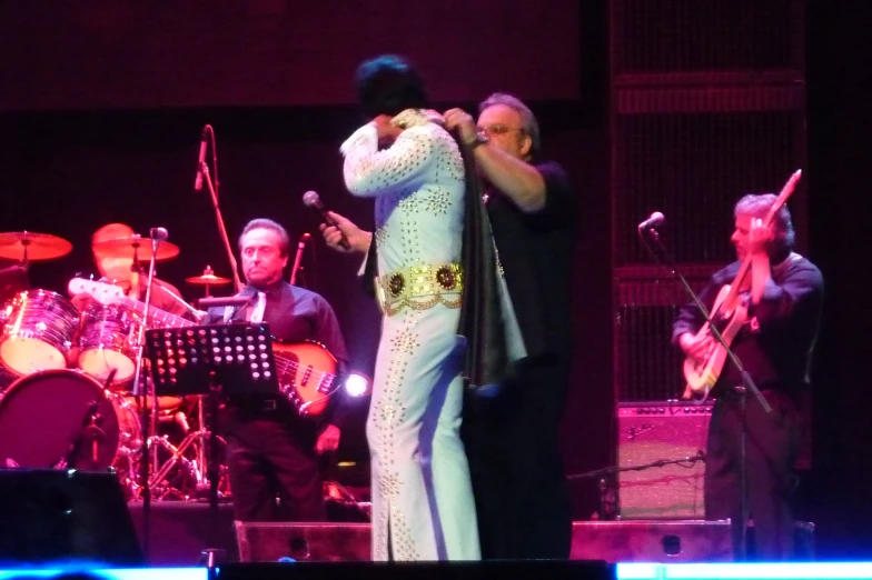 elvis singer on stage with musicians in background