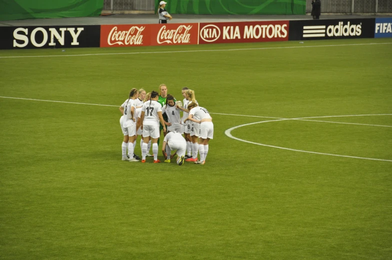 several female soccer players standing around talking on a field