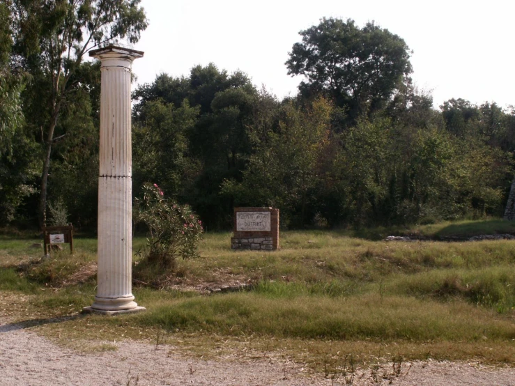 an old pillar and monument in a small area with lots of grass