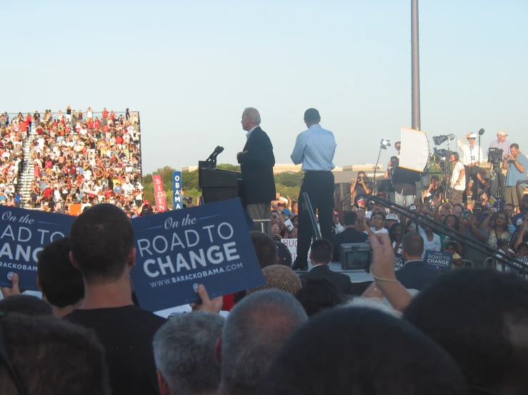 two men standing on top of a podium during a political rally