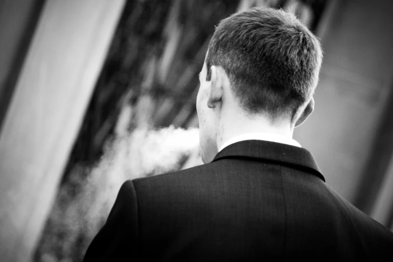 the man is smoking a cigarette outside in black and white