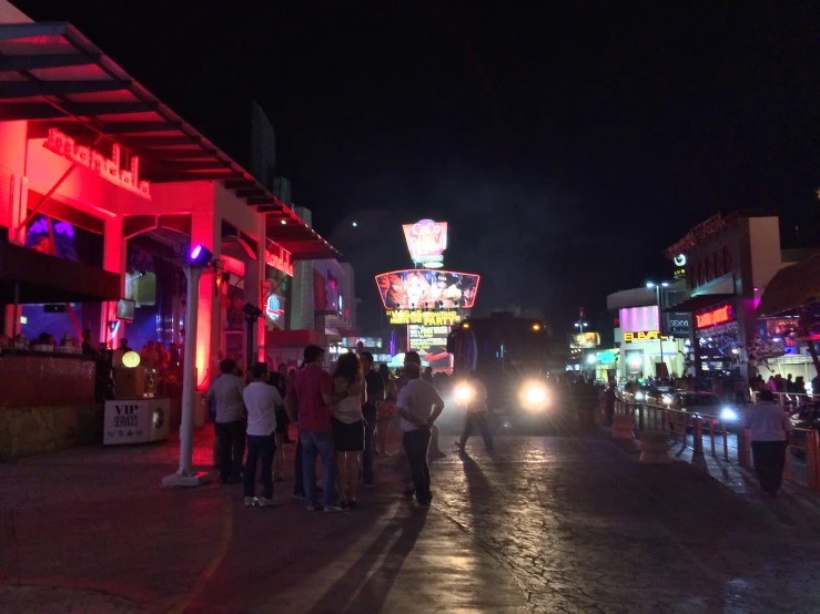 cars driving on the street near some brightly lit buildings