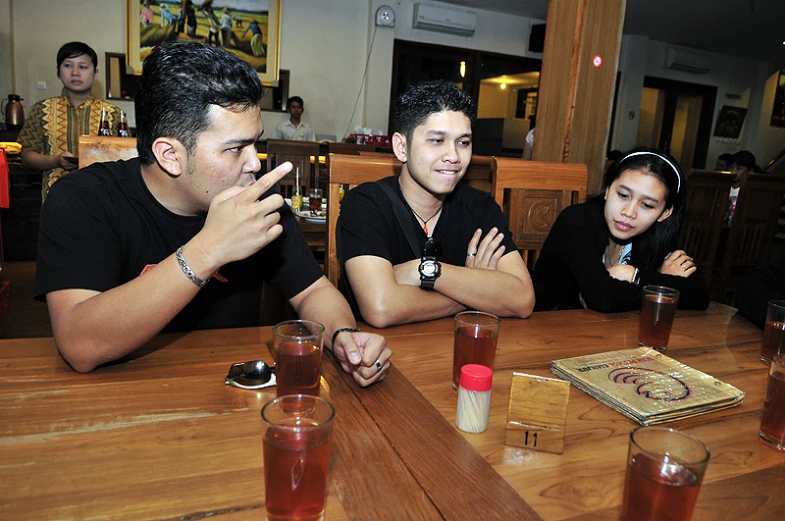 three people sitting around a table with some beverages