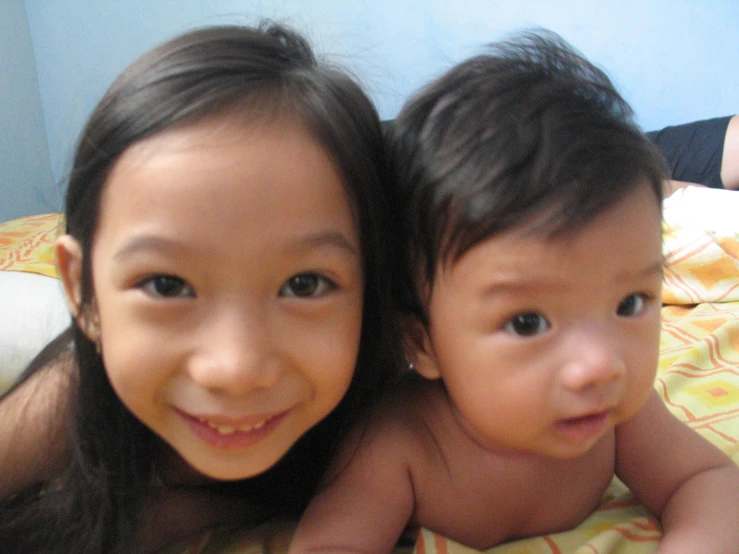 two children sitting on a bed and smiling