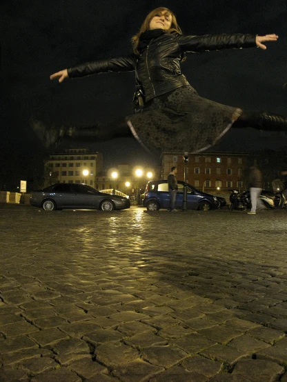 a woman is playing outside at night with her arms outstretched