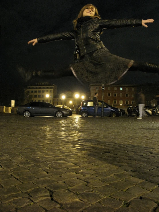 a woman is playing outside at night with her arms outstretched