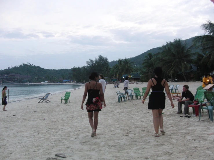 two women walking along the beach by chairs