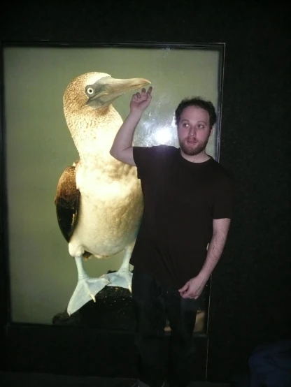 a man standing next to a white bird in front of a mirror