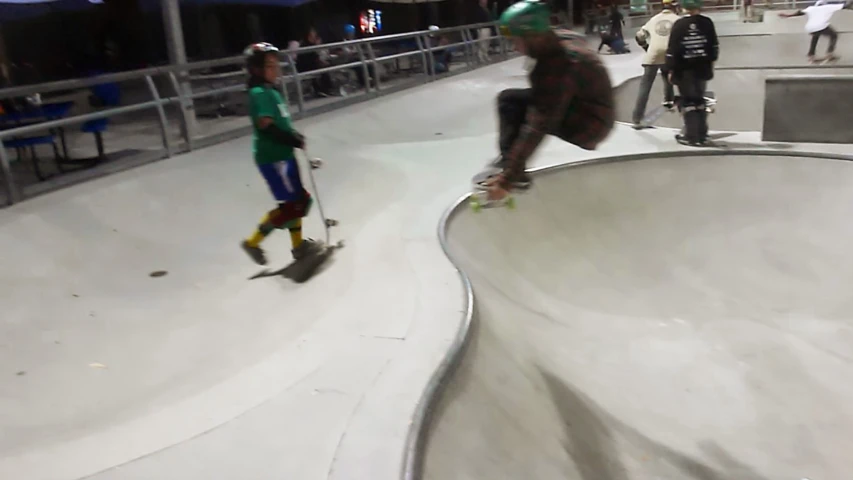 a man skating on the skateboard track while another guy stands next to him