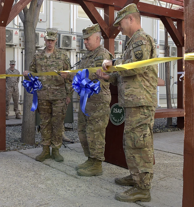 four men in military uniforms hold blue ribbon