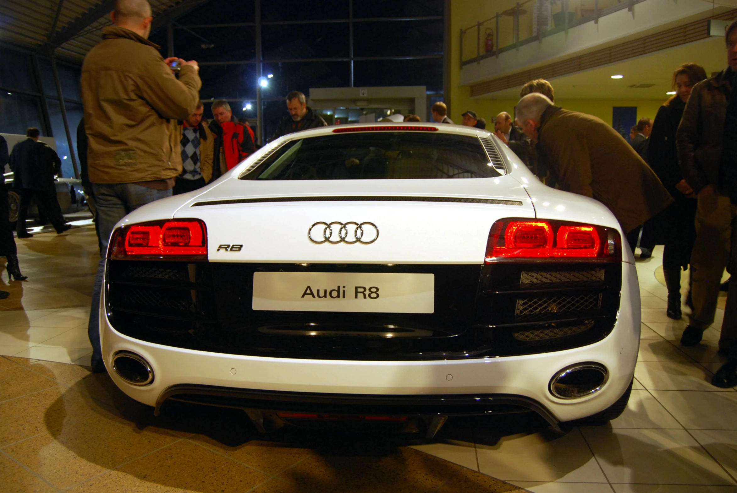 a white car is on display in a large crowd