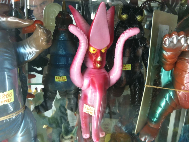 a red and pink balloon in the shape of a monster is sitting between other toys