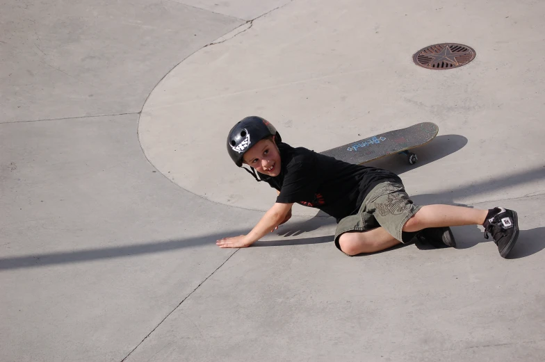 a boy sits on the ground with a skateboard