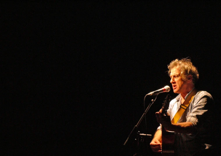 a man with a guitar and microphone in front of a microphone