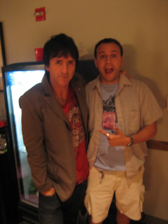 two men are standing in front of an empty fridge