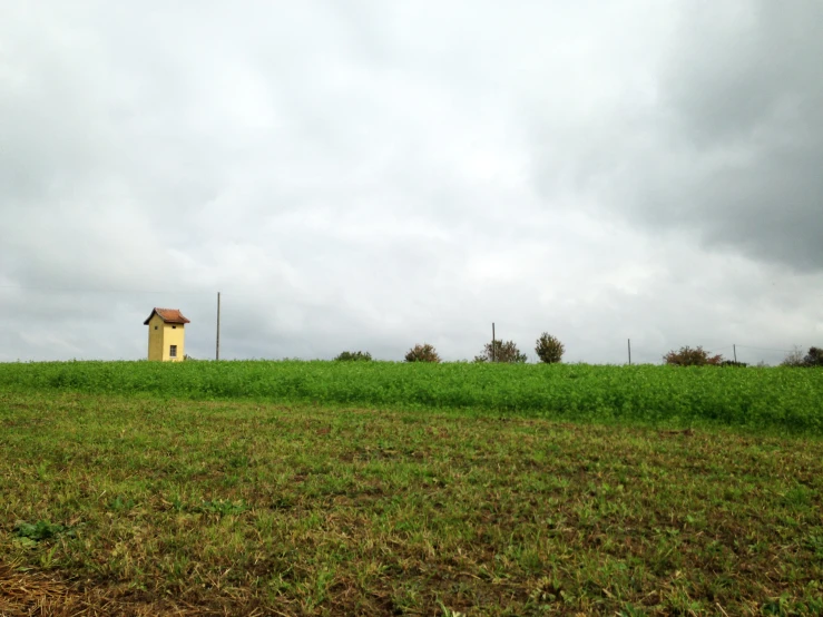 a lone house sits alone in a large green field