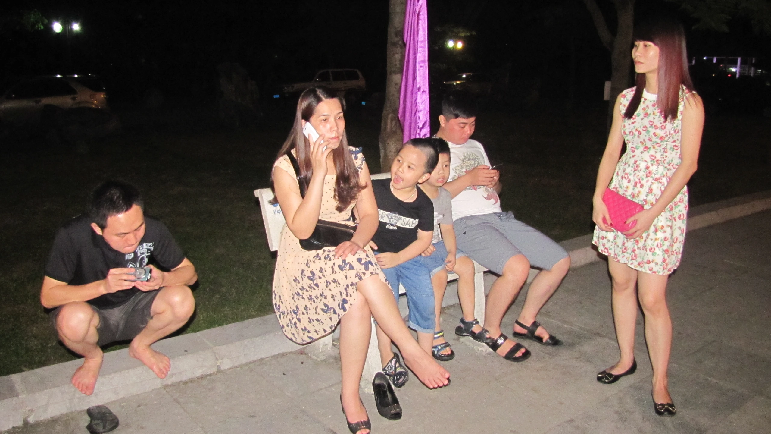 an asian family sits together at night in front of a sign