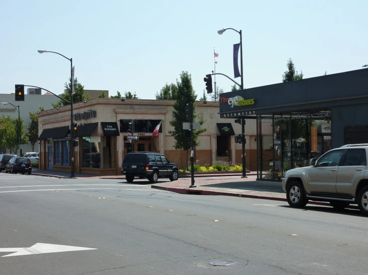 cars driving down a city street past a small building