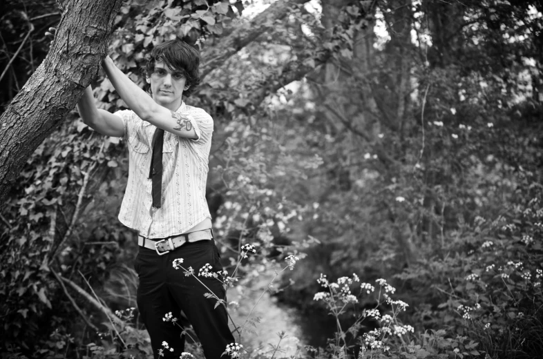 a man standing near a tree holding his hands up to his head