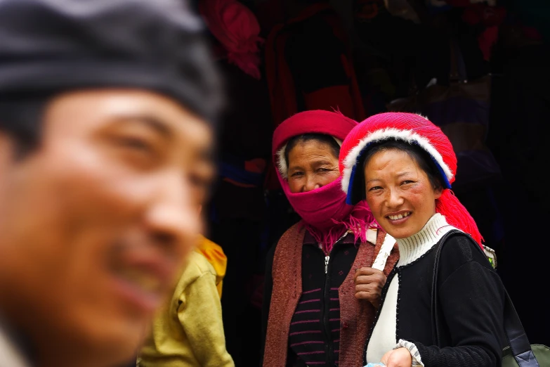 two women smile at the camera with other people behind them