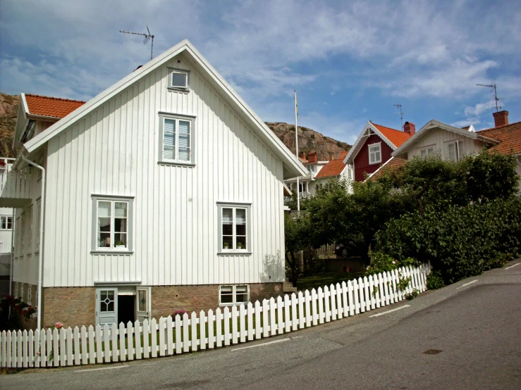 white fence surrounding house with two windows on hill