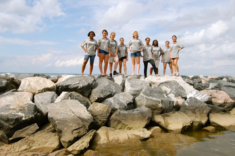 a group of people standing on top of rocks next to a lake