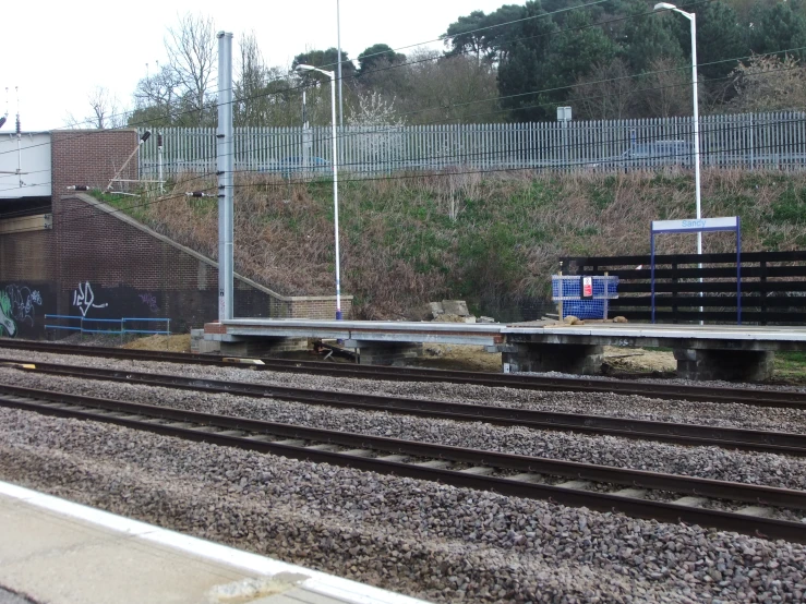 a blue and black bench sitting on some train tracks