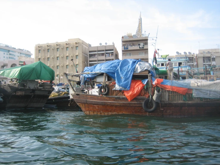 a wooden boat floating in a harbor next to a row of buildings