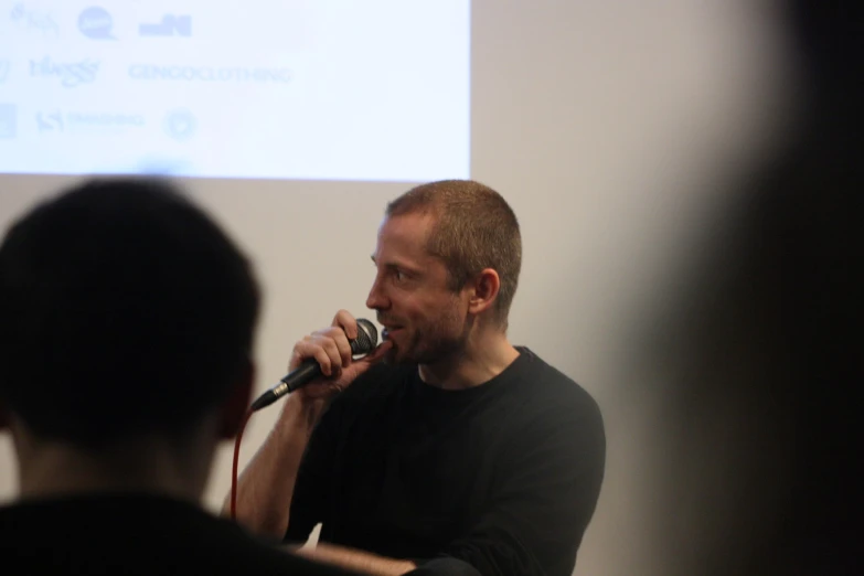 a man in black shirt holding a microphone near his face