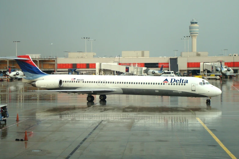 an airplane is parked in a rain covered airport lot