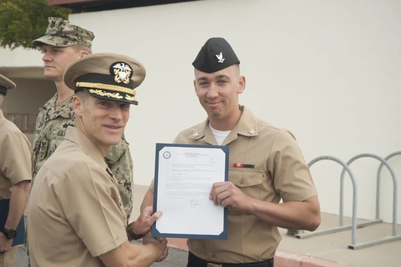 a man in uniform standing next to another man holding a plaque