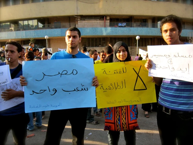 people holding signs and standing in front of an office building