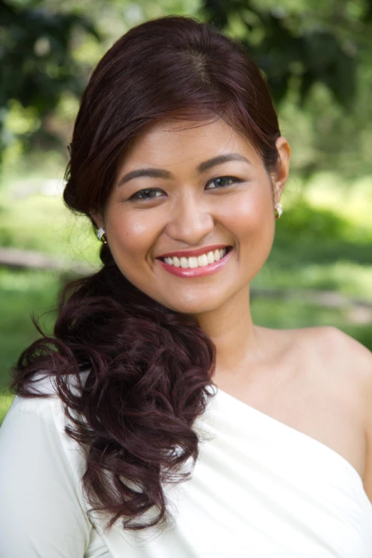 a woman wearing a white dress smiles at the camera